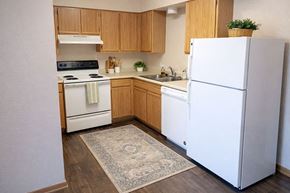 Hays apartment for rent - A kitchen with a white fridge and wooden cabinets.