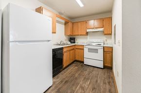 Marshalltown apartment for rent - A kitchen with a white fridge, white stove, and wooden cabinets.