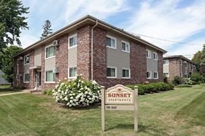 Wisconsin Rapids apartment for rent - A Sunset Apartments sign is in front of a brick apartment building.