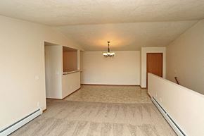 Kaukauna apartment for rent - A spacious room with a carpeted floor and a chandelier hanging from the ceiling.