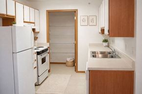 Hays apartment for rent - A kitchen with a white refrigerator, wooden cabinets, and a white sink.