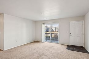 New Richmond apartment for rent - A white room with a carpeted floor and a sliding glass door leading to a balcony.