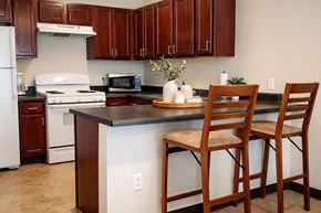 Chanute apartment for rent - A kitchen with wooden cabinets and a white stove.
