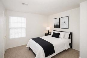 Hugoton apartment for rent - A bedroom with a bed, nightstand, and two pictures on the wall.