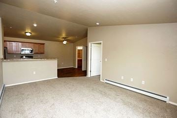 Kronenwetter apartment for rent - A living room with a carpet floor and a kitchen area in the background.