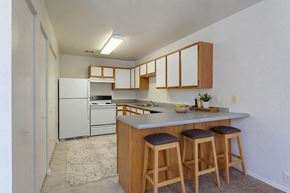 Liberal apartment for rent - A kitchen with white appliances and wooden cabinets.