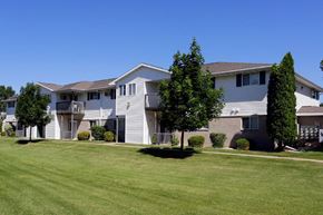 Neenah apartment for rent - an apartment building with a green lawn and trees
