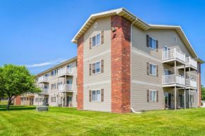 Oskaloosa apartment for rent - A large apartment building with a red brick chimney and a balcony on the second floor.