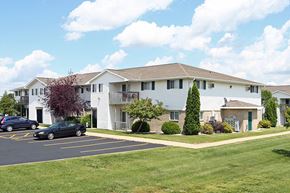 Kaukauna apartment for rent - A black car is parked in a parking lot in front of a white building.