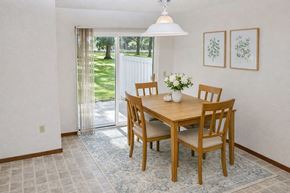 Waseca townhouse for rent - A dining room with a table and chairs and a view of a lawn outside.