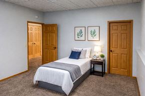 Greenfield apartment for rent - A bedroom with a bed, nightstand, and two doors.