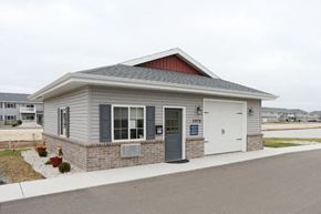 Oshkosh apartment for rent - a small gray building with a white door and a sidewalk