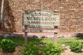 Appleton apartment for rent - A sign for W. Wilson Apartments is displayed in front of a brick wall.