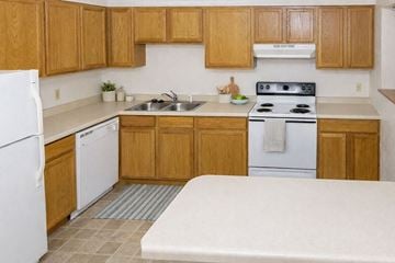 Waseca townhouse for rent - A kitchen with wooden cabinets and a white stove top oven.