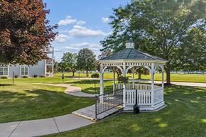 Oshkosh townhouse for rent - A gazebo with a white railing is surrounded by a green lawn.