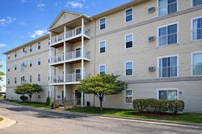 Port Huron apartment for rent - Apartment building with balconies and trees in front.
