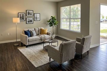Tulsa apartment for rent - A living room with a grey couch, two chairs, and a table with a plant on it.