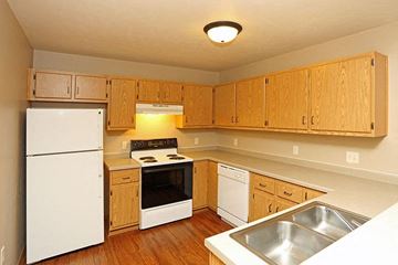 Rhinelander apartment for rent - a kitchen with white appliances and wooden cabinets