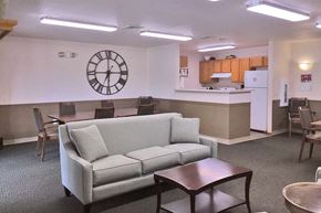 Muskego apartment for rent - A living room with a grey couch, a brown coffee table, and a clock on the wall.