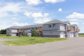 Kronenwetter apartment for rent - A large building with a grey roof and a parking lot in front.