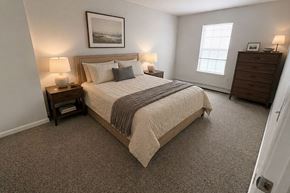 Port Huron apartment for rent - A bedroom with a large bed, two lamps, and a picture on the wall.