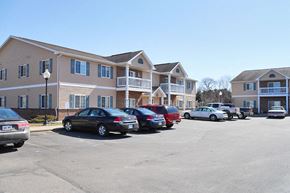 Richland Center apartment for rent - A parking lot with cars and apartment buildings in the background.