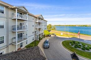 Port Huron apartment for rent - A car is parked on a curved driveway in front of a building with balconies.