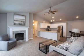 Sister Bay apartment for rent - A living room with a grey couch, a fireplace, and a ceiling fan.