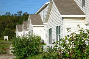 Duluth apartment for rent - A white house with a brown roof is surrounded by greenery.