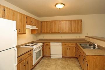 Platteville apartment for rent - a kitchen with wooden cabinets and a white stove and refrigerator