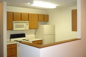 Carroll apartment for rent - a kitchen with white appliances and wooden cabinets