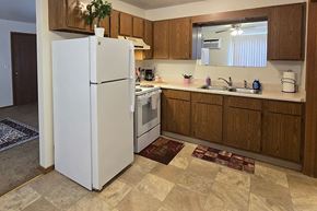 Shawano apartment for rent - A white refrigerator in a kitchen with wooden cabinets.