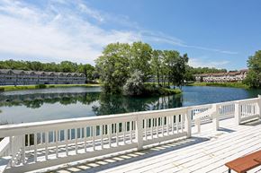 Hartland apartment for rent - A wooden deck overlooks a body of water with a row of houses in the distance.