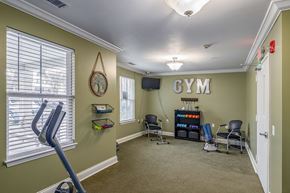 Alliance apartment for rent - A gym room with a treadmill, exercise equipment, and a flat screen TV.