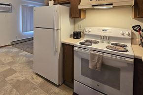 Shawano apartment for rent - A white refrigerator stands next to a white stove in a kitchen.