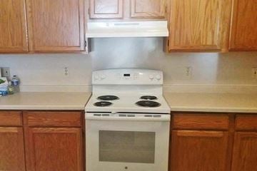 Muskego apartment for rent - A white stove top oven with a glass door is in a kitchen with wooden cabinets.