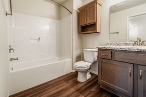 Plover apartment for rent - A white toilet sits in a bathroom with wooden floors and a wooden medicine cabinet.