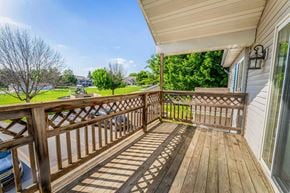Newton apartment for rent - A wooden deck with a railing and a view of a grassy area and trees.