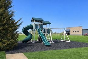 Boone apartment for rent - A green and white playground with a slide and a swing set.
