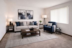Carlinville apartment for rent - A living room with a grey couch, a blue chair, a wooden coffee table, and two lamps.