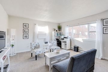 South Bend apartment for rent - A living room with a grey chair and a white table.