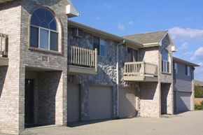 Neenah apartment for rent - a brick house with a balcony and garage doors