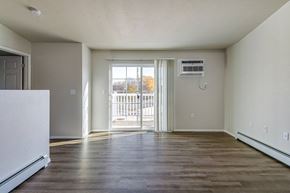 Neenah apartment for rent - A spacious room with a white fridge and a sliding glass door leading outside.