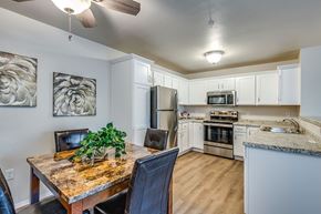Neenah apartment for rent - A kitchen with a table and chairs in the foreground and a refrigerator, microwave, oven, and stove in the background.