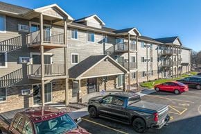 Onalaska apartment for rent - A red pickup truck is parked in a parking lot in front of a building with a balcony.