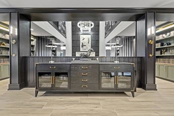 A large black credenza with brass pulls sits in the middle of a room with a large