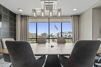 A conference room with a table and chairs and a large window with an american flag