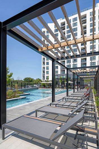 A pool area with sun loungers and a building in the background