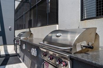 A row of stainless steel grills with a red and white sign on the front