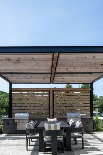 A wooden pergola with a table and chairs underneath it